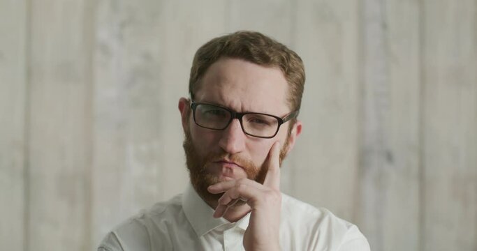 Serious man with glasses in office looking at camera and points his finger