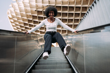 Fototapeta na wymiar Black teenage girl jumping happily on escalator