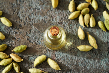 A bottle of essential oil with cardamom seeds in sunlight