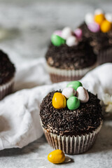 Homemade Easter chocolate cupcakes with chocolate butter cream frosting and candy eggs. Easter brunch. spring blossom decoration. on white linen tableclouth Happy easter day. Easter recipes.
