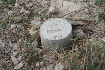 Boundary mark stone of Thailand Department of Lands on ground. Thai characters read that Lak Khet...