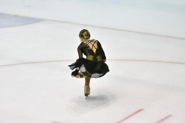 Girl figure skater rolls on a skating rink with artificial ice 