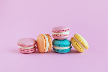 Tasty french macaroons on a violet pastel background.