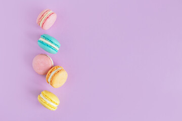 Tasty french macaroons on a violet pastel background.