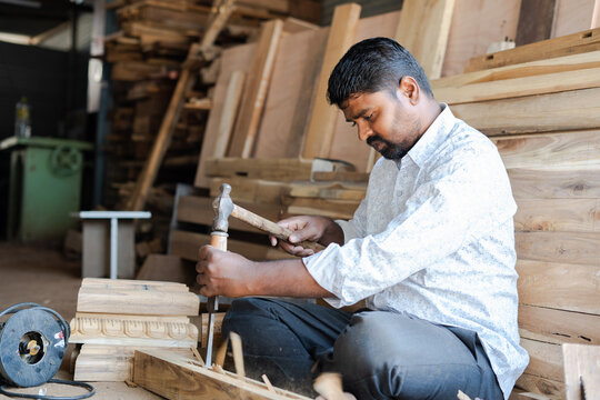 Indian carpenter making wood design by using carpentry tools at workplace - concept of skilled occupation, creativity and local artisans.