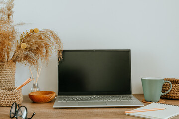 Empty screen of laptop, dried flowers pampas grass in the jute vase