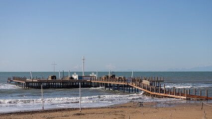 Fototapeta premium Beautiful sea panton and beach. A large wooden pier is on the sandy beach of the resort. Beautiful view of the tropical coast with a long pantone. Landscape of the sea coast