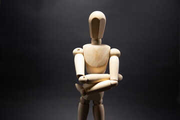 The wooden mannequin stand cross one's arm. on a black background