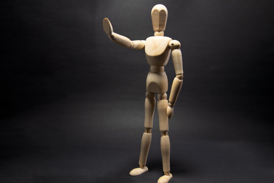 The wooden mannequin raising arm and stop. on a black background
