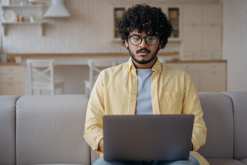 Pensive Indian man using laptop computer searching online looking at digital screen. Serious asian...