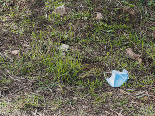 Mask thrown in the field as garbage, polluting nature. Lack of awareness concept