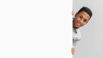 African American Boy Posing With Empty Board On Gray Background © Prostock-studio