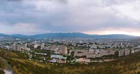Fototapeta na wymiar Aerial view from Monument History of Georgia mount, North of Tbilisi. Dramatic gray weather, overcast sky. Day time. Gldani Nadzaladevi