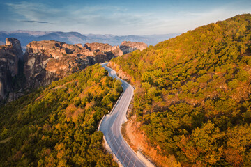 Aerial top view over scenic serpentine roads among dense forest near Meteora monasteries in Greece