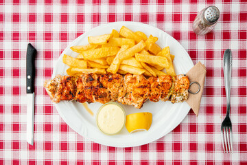 knife and fork with traditional Greek grilled meat barbecue - souvlaki with french fries. Fastfood and healthy diet concept