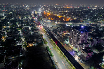 Fototapeta na wymiar aerial drone shot with elevated metro train tracks over busy street with light trails from traffic skyscrapers on side in hyerabad jaipur india
