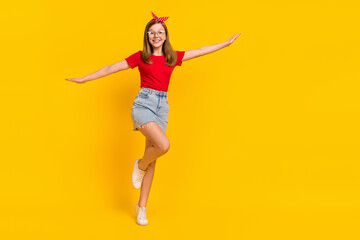 Fototapeta na wymiar Full size photo of positive sweet cute teen girl dancing have fun hands flying wings isolated on yellow color background