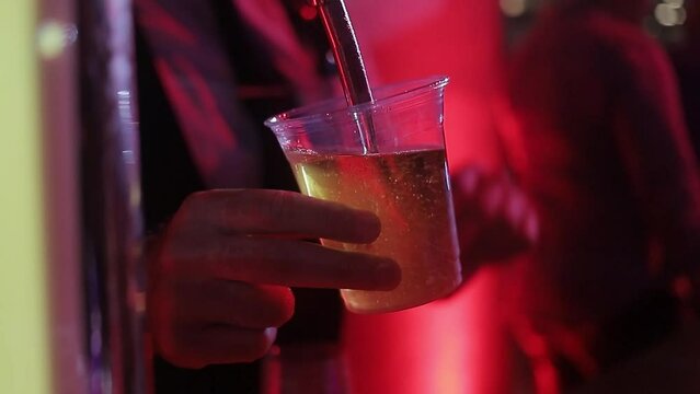 bartender sirviendo cerveza en vaso plastico, toma cerrada en discoteca nocturna