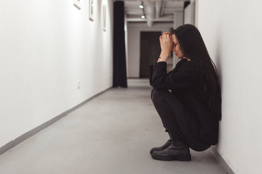Stressed overworked young business woman sitting on floor. Fired and depressed in office.