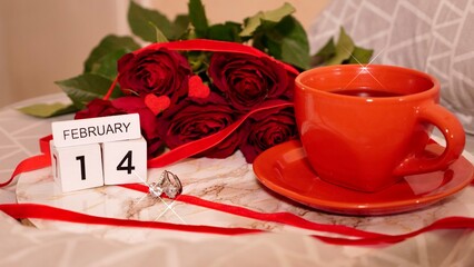 Background Festive Flatlay, composition for Valentine's Day on February 14. Coffee in a red cup, red rose flowers and diamond heart earrings at home in bed