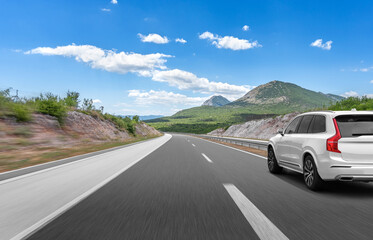 White car on a scenic road. Car on the road surrounded by a magnificent natural landscape.