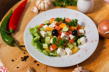 greek salad with feta cheese and olives on a white plate and a wooden background