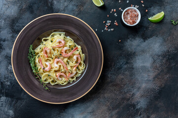 Seafood tagliatelle pasta with grilled shrimps, bechamel sauce and thyme, fettuccine pasta. Italian food. Healthy diet seafood concept. Top view