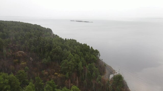 Karelia, Onega Lake, Petrozavodsk Bay. Aerial video showing the forest and the coast, near the botanical garden. The water surface of the lake and the autumn forest. Vacation in Russia concept.