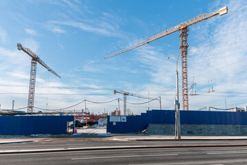Construction cranes at the construction site against the blue sky. Construction of a new building.  New district construction concept..