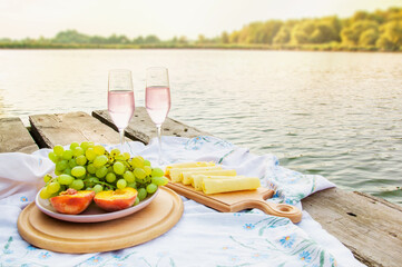 delicious food with wine for a romantic picnic by the river, summer, dawn. High quality photo