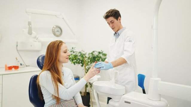 Young female patient in dental chair rinsing mouth with water before during dentist appointment