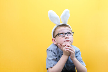 A happy boy with glasses has put on rabbit ears and is dreaming . Sleep awaits the Easter holiday.