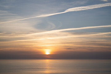 Portugal ocean sunset. Portuguese sky and sea. Pastel sunset with lines from airplanes. Airplane trails on sunset