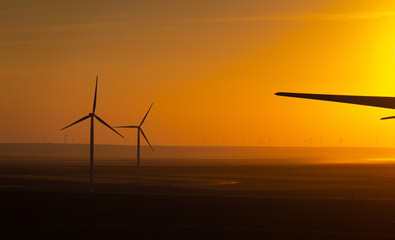 Sunset over an eolian wind farm with amazing sky color. Alternative eco energy good for the environment. Renewable energy industry.