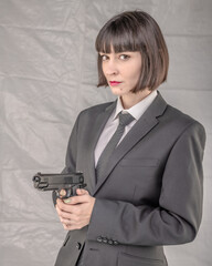 Formidable young woman with bobbed hair, wearing suit and tie and brandishing a pistol