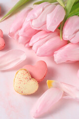 Fototapeta na wymiar French sweet cookies macarons macaroons in heart shape and pink tulip flowers on marble background