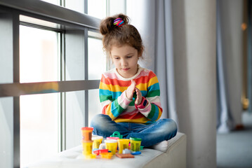 A little girl sculpts from plasticine.