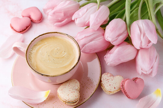 Vintage pink coffee cup, tulip flowers and french sweet cookies macarons macaroons on marble background - Powered by Adobe