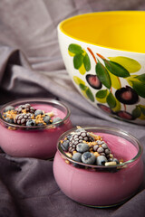 Fresh summer vegan tasty violet creamy dessert with organic blackberries and almonds in a jar on the table  with yellow bowl in the background. Food concept idea.