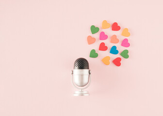 A silver black microphone next to which are hearts of different colors. Minimal concept of...