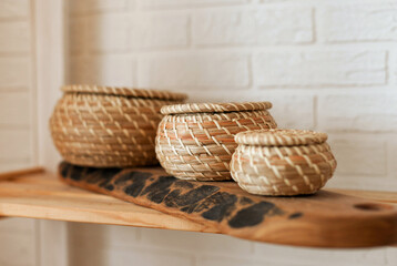 Fototapeta premium Cleaning and organizing - three eco wicker neutral tones baskets on wooden shelf at minimal home. Storage in the kitchen at minimal home
