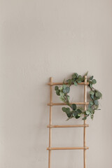 A staircase and green wreath near beige wall, minimalist background with copy space left. Minimal background scandinavian interior style.