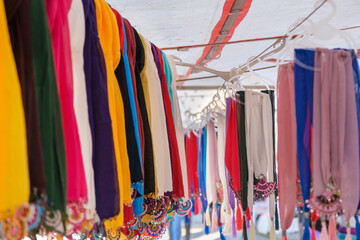 Colorful handmade scarves lined up on a rope hanger in woman producer bazaar in Odemis, Izmir. Many or lots of different beautiful modern style needlework or needle lace scarves hanging on a rope.