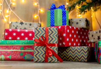 a large pile of gift boxes wrapped in red and beige wrapping paper and ribbons under a Christmas tree on a bokeh background