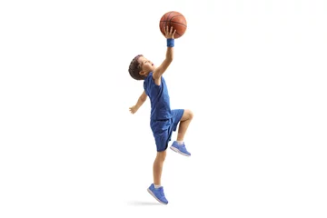 Tuinposter Full length profile shot of a boy in a blue jersey jumping with a basketball © Ljupco Smokovski