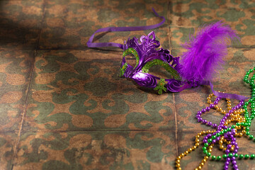 Mardi gras carnivale mask, green, purple, yellow beads on rustic tile background - obrazy, fototapety, plakaty