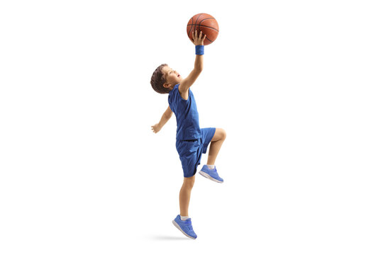 Full length profile shot of a boy in a blue jersey jumping with a basketball