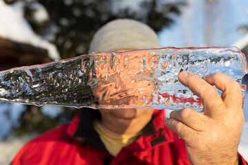 a man is holding a piece of ice in his hands. Selective focus.