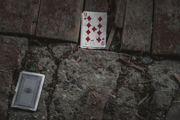 Playing cards thrown on dirty abandoned place, diamonds cards.