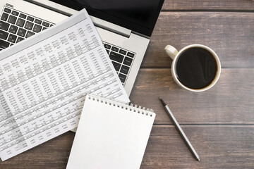 Financial document on laptop keyboard. Notepad and a cup of coffee. Business and financial concept